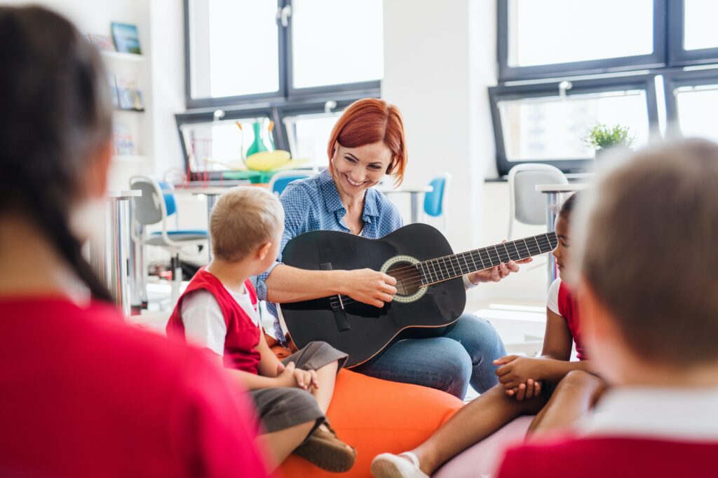 guest speaker playing guitar and singing songs with children in classroom