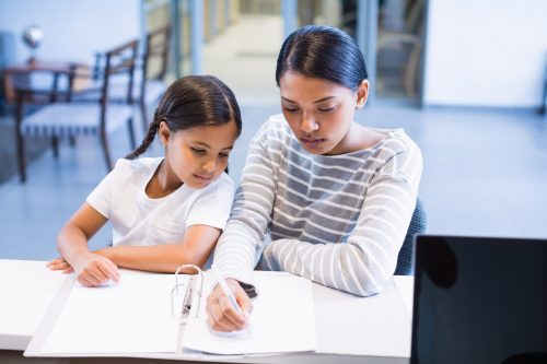 Mother and daughter filling out paperwork at counter in hospital