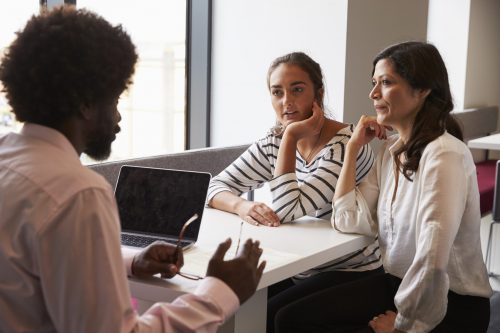 teacher explaining paperwork to mother and daughter